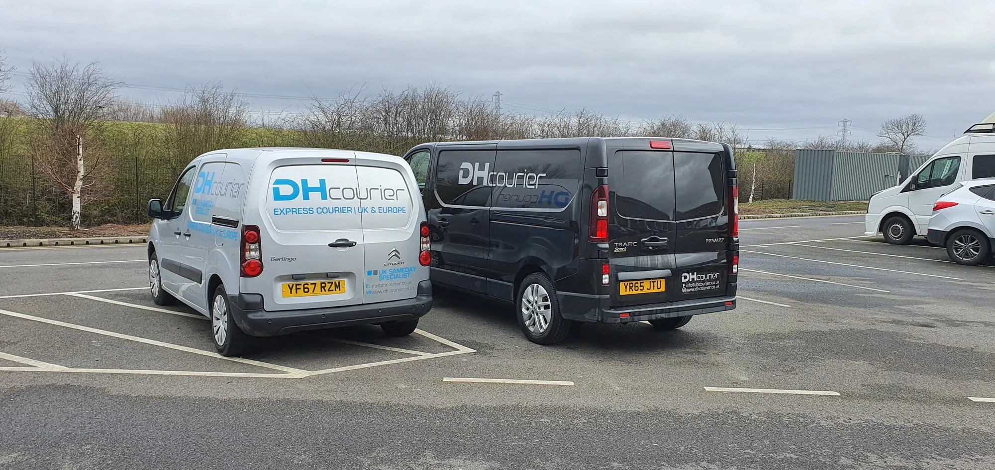 Two DH Courier vans parked side by side, a small Citroen and a Renault Trafic, both in company livery